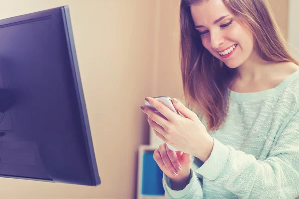 Vrouw met behulp van haar telefoon in haar kantoor aan huis — Stockfoto