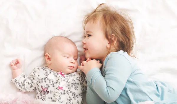 Batole dívka si hraje s její novorozence sestrou — Stock fotografie