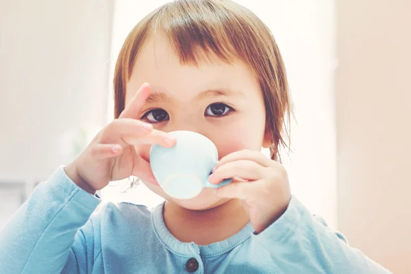 Gelukkig peuter meisje drinken uit een theekopje Stockfoto