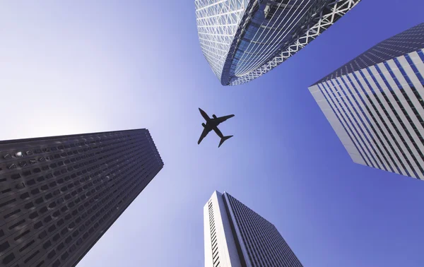 Airplane flys between tall city buildings — Stock Photo, Image