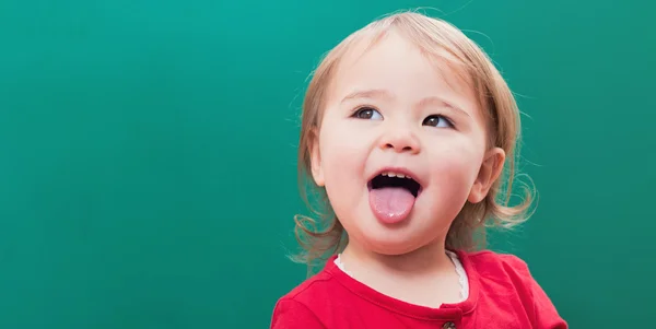 Chica sacando la lengua delante de una pizarra —  Fotos de Stock