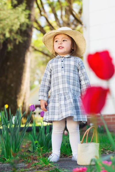 Menina criança em um chapéu explorando seu jardim — Fotografia de Stock