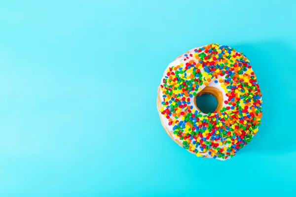 Rosquilla espolvoreada sobre fondo azul pastel —  Fotos de Stock