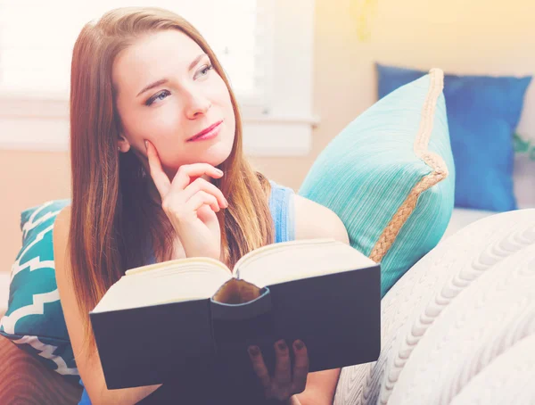 Mulher lendo um livro em seu sofá — Fotografia de Stock