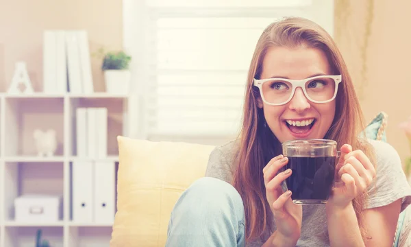 Kvinna som dricker kaffe på hennes soffa — Stockfoto