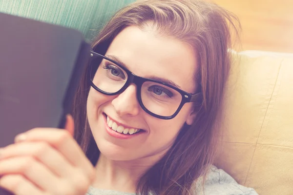 Mulher lendo um e-book em seu sofá — Fotografia de Stock