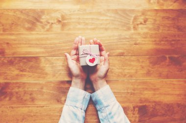 Bir hediye kutusu ahşap masa üzerinde tutan kadın