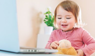 onun oyuncak ayı ile bir dizüstü bilgisayar kullanan kız