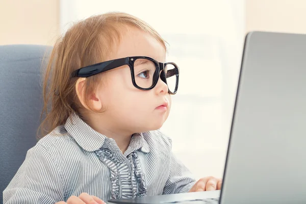 Kleuter meisje met grote glazen op haar laptop — Stockfoto