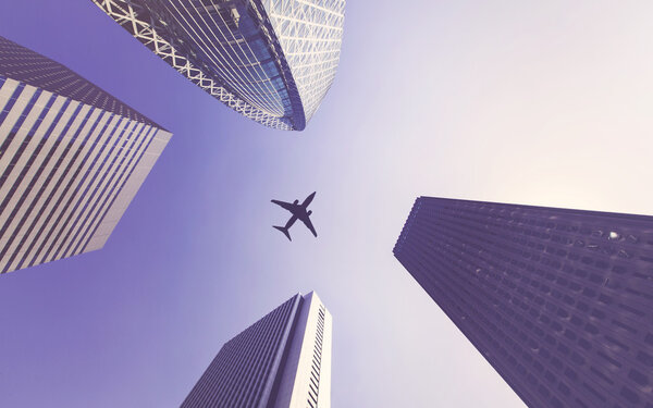 Airplane appears between tall city buildings