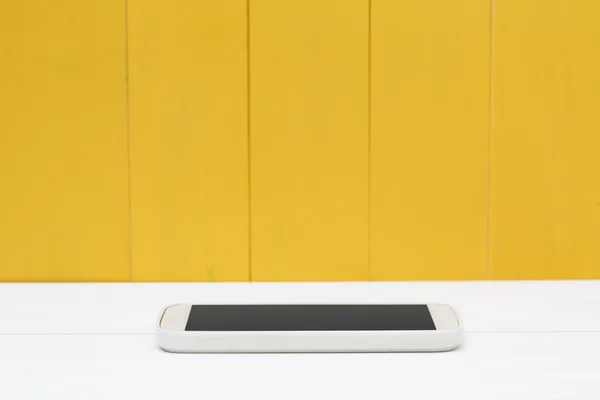 Smartphone blanco con pared de madera amarilla —  Fotos de Stock