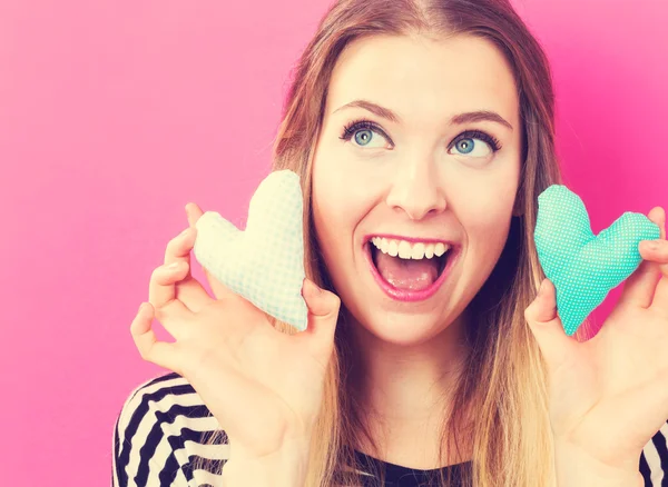 Mujer feliz sosteniendo cojines del corazón — Foto de Stock