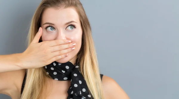 Młoda kobieta zakrywa usta — Zdjęcie stockowe