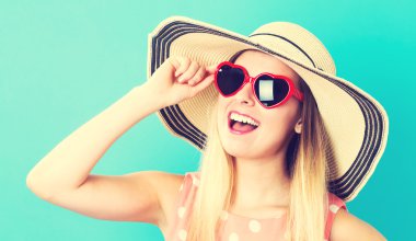 Şapka ve güneş gözlüğü giyen mutlu kadın