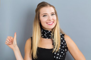 Mutlu genç bir kadın başparmağını kaldırıyor.