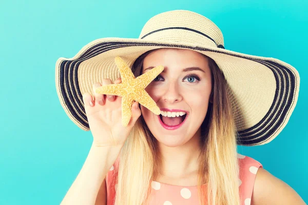 Glückliche junge Frau hält einen Seestern in der Hand — Stockfoto