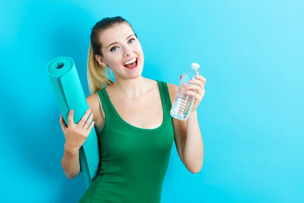 Yoga minderi ve su şişesi tutan kadın — Stok fotoğraf