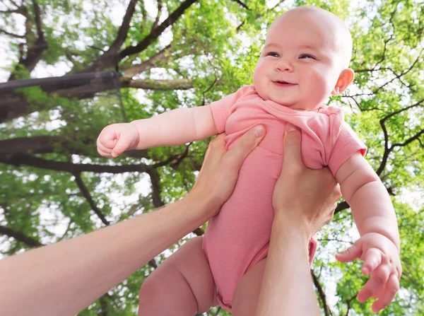 Happy spädbarn flicka som hålls i luften — Stockfoto