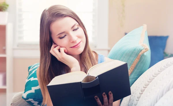 Kvinna läser en bok på hennes soffa — Stockfoto