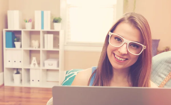 Vrouw met behulp van haar laptop op haar bank — Stockfoto