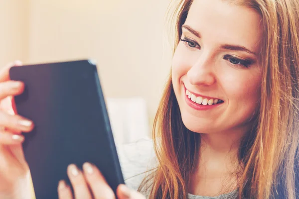 Mulher feliz lendo um e-book em seu sofá — Fotografia de Stock