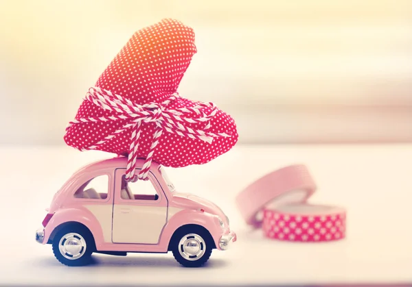Carro em miniatura carregando almofada de coração — Fotografia de Stock