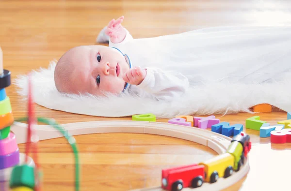 Noworodka dziewczynka leżąc w jej domu z zabawkami — Zdjęcie stockowe