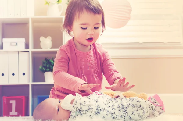 Onun bebek kardeşi ile oynarken yürümeye başlayan çocuk kız — Stok fotoğraf