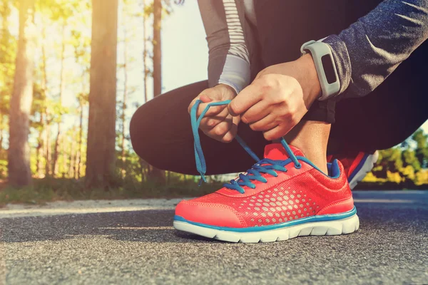 Vrouwelijke jogger koppelverkoop haar schoenen buiten — Stockfoto