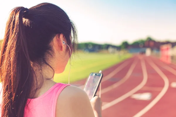 Kvinnliga idrottare lyssna på musik på en löparbana — Stockfoto
