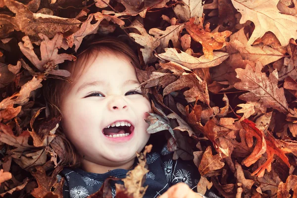 Girl smiling in leaves — Stock Photo, Image