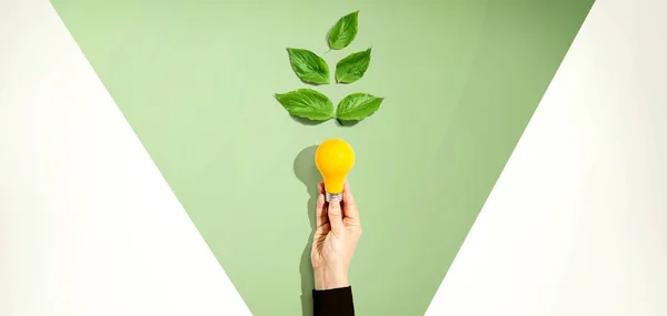 Persona sosteniendo una bombilla con hojas verdes — Foto de Stock