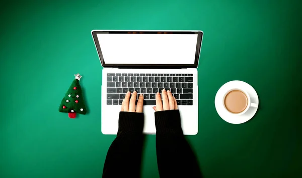 Πρόσωπο που χρησιμοποιεί φορητό υπολογιστή με μαξιλάρι χριστουγεννιάτικου δέντρου και φλιτζάνι καφέ — Φωτογραφία Αρχείου