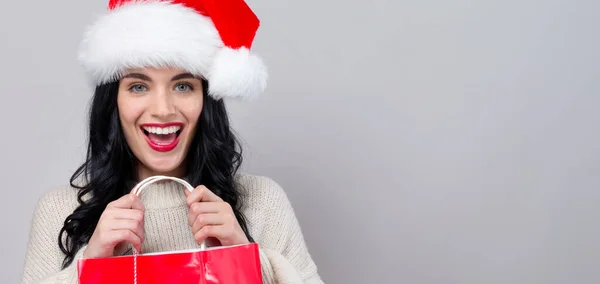 Jonge vrouw met kerstmuts met een boodschappentas — Stockfoto