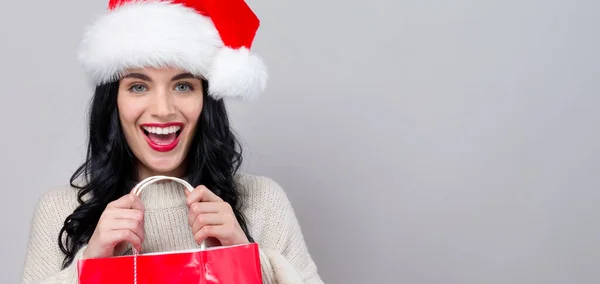 Mujer joven con sombrero de santa sosteniendo una bolsa de compras — Foto de Stock