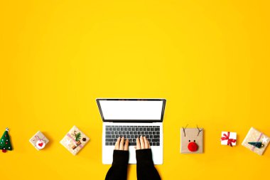 Noel hediyesi kutuları olan bir dizüstü bilgisayar kullanan kişi.