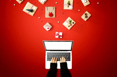 Noel hediyesi kutuları olan bir dizüstü bilgisayar kullanan kişi.