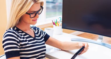 Mutlu genç kadın tabletini kullanıyor.