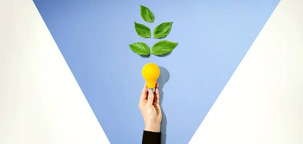 Pessoa segurando uma lâmpada com folhas verdes — Fotografia de Stock