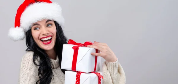 Junge Frau mit Weihnachtsmütze hält Geschenkschachteln in der Hand — Stockfoto