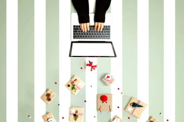 Noel hediyesi kutuları olan bir dizüstü bilgisayar kullanan kişi.