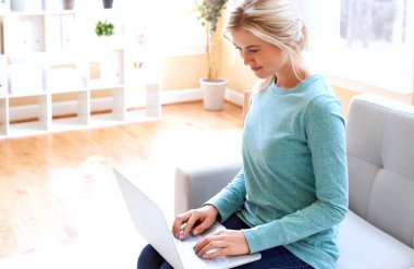 Dizüstü bilgisayarını kullanan genç bir kadın.