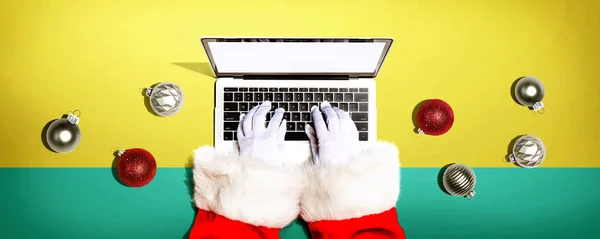 Santa Claus za pomocą laptopa z bombkami świątecznymi — Zdjęcie stockowe