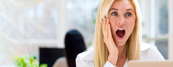 Surprise jeune femme assise à son bureau — Photo