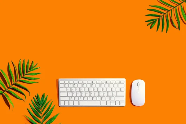 Computer keyboard and mouse with tropical plants