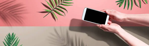 Smartphone con hojas de palma tropical y sombra — Foto de Stock