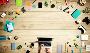 Ofis malzemesi olan bir dizüstü bilgisayar kullanan kişi.