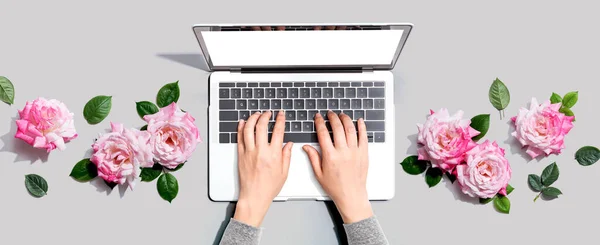 Woman using her laptop with pink roses