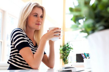 Masasında oturan genç bir kadın.