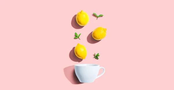 Φρέσκα κίτρινα λεμόνια με θέα στο φλιτζάνι τσάι — Φωτογραφία Αρχείου